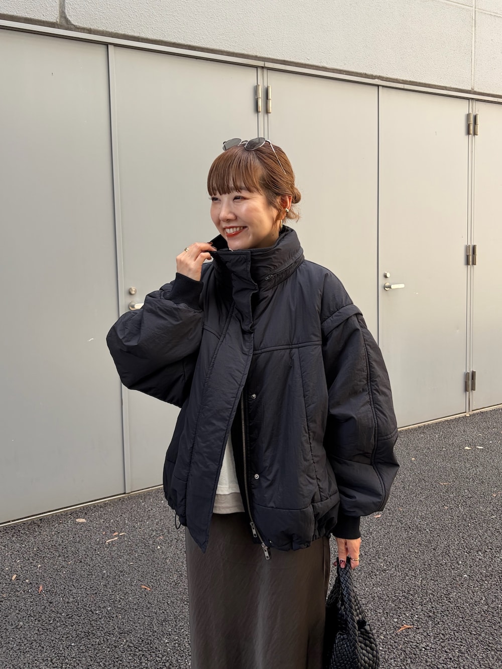ブラック系のブルゾン、ホワイト系のTシャツ/カットソー、グレー系のスカートを着用したレディースの夏コーディネートの4枚目の写真