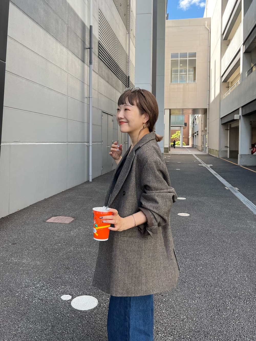 ブラウン系のテーラードジャケット、ブルー系のデニムパンツ、ブラック系のトートバッグを着用したレディースの夏コーディネートの4枚目の写真