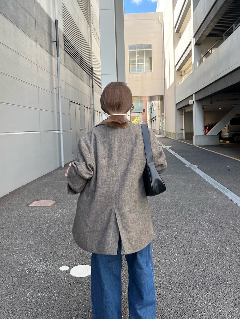 ブラウン系のテーラードジャケット、ブルー系のデニムパンツ、ブラック系のトートバッグを着用したレディースの夏コーディネートの5枚目の写真