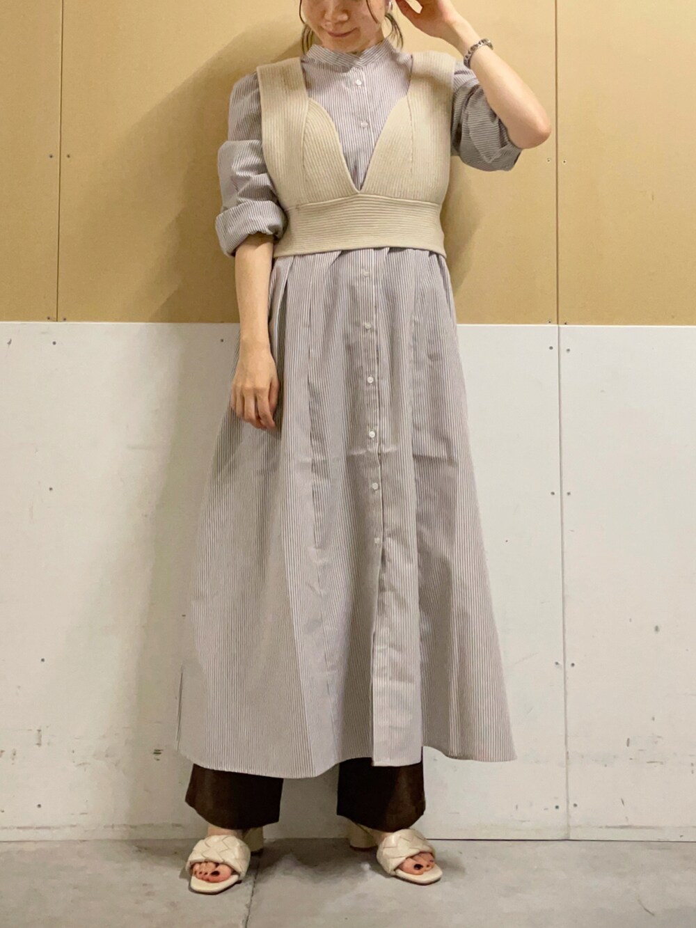 ホワイト系のトートバッグ、ベージュ系のベスト、ベージュ系のシャツワンピースを着用したレディースの夏コーディネートの2枚目の写真