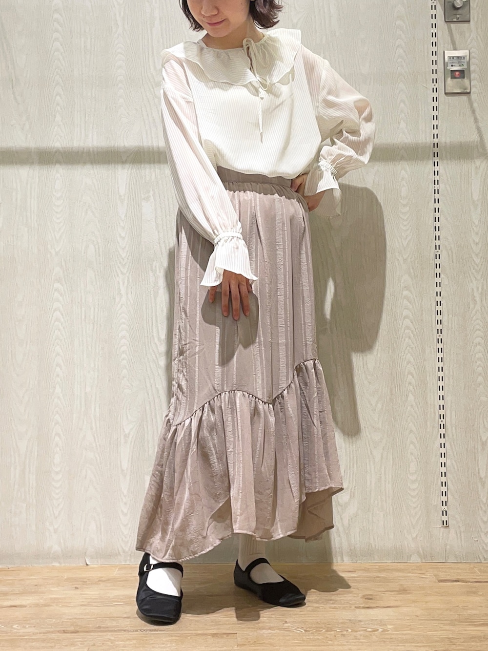ベージュ系のスカート、ホワイト系のシャツ/ブラウス、ホワイト系のタンクトップを着用したレディースの春コーディネートの2枚目の写真