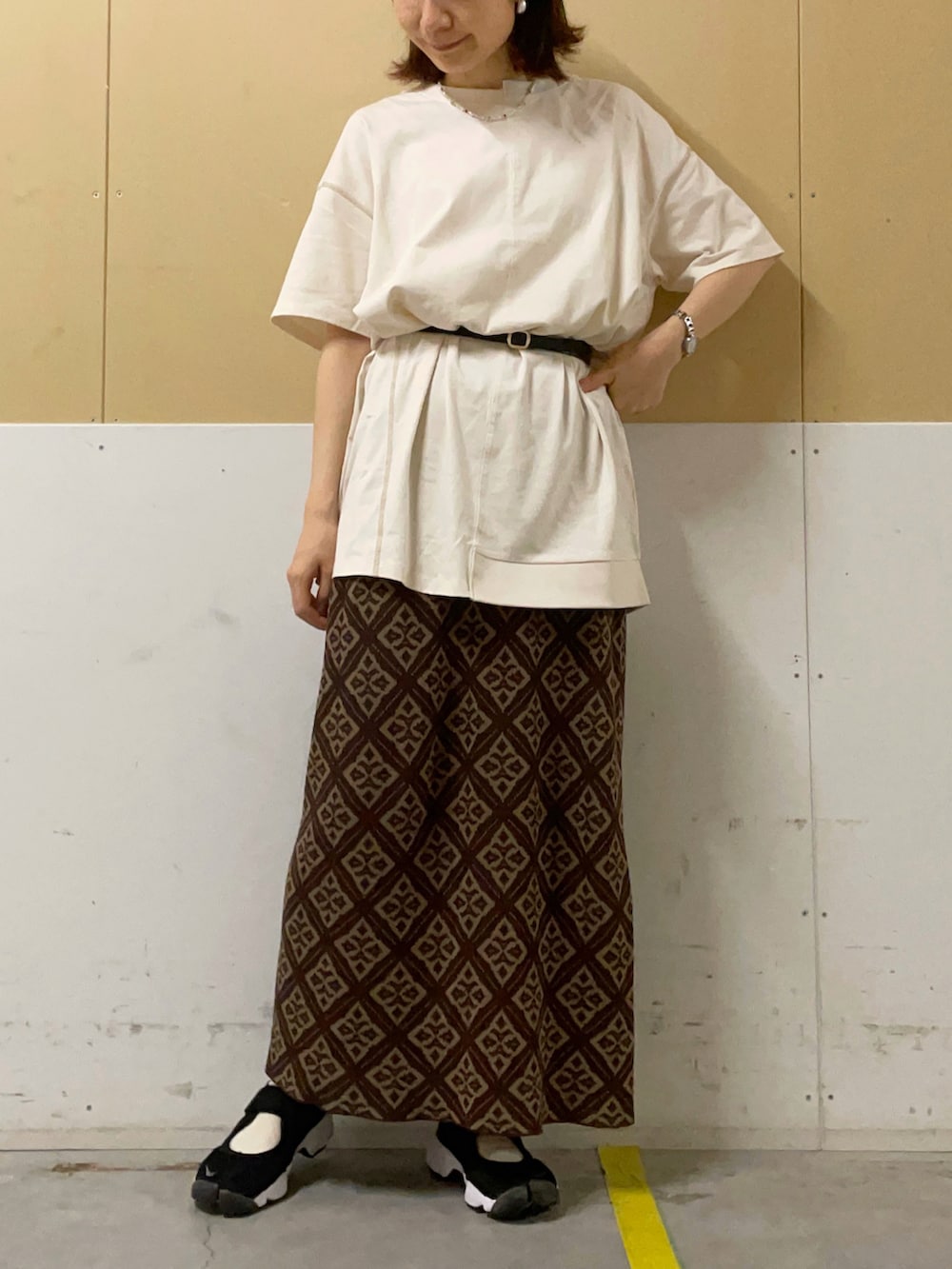 ブラック系のトートバッグ、ブラウン系のスカート、ホワイト系のTシャツ/カットソーを着用したレディースの夏コーディネートの2枚目の写真