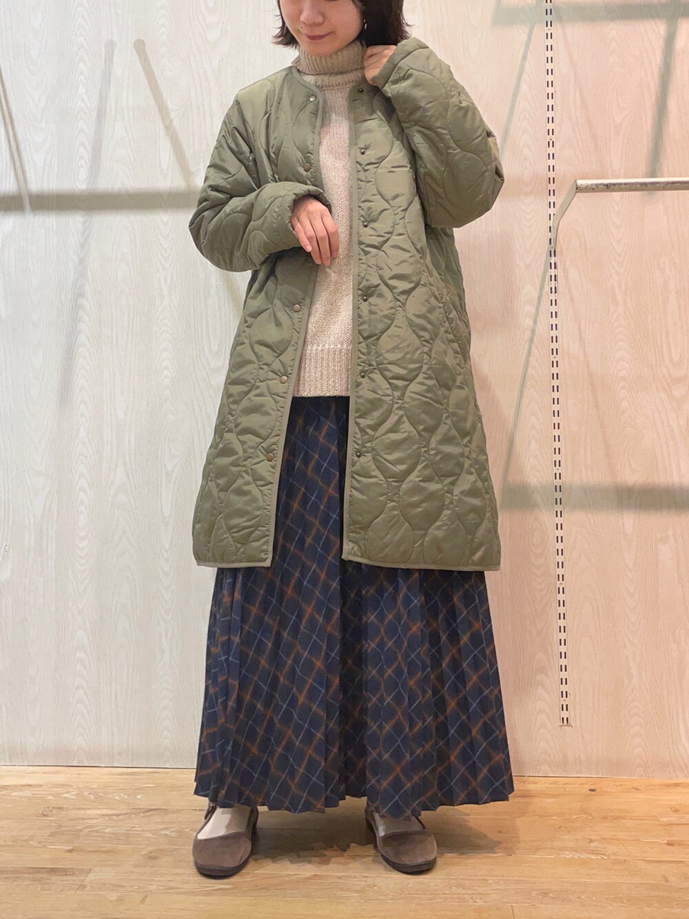 ベージュ系のトートバッグ、ブルー系のスカート、グリーン系のその他アウターを着用したレディースの冬コーディネートの2枚目の写真