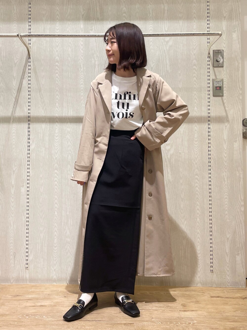 ブラック系のシャツ/ブラウス、ブラック系のスカート、ベージュ系のトレンチコートを着用したレディースの冬コーディネートの2枚目の写真