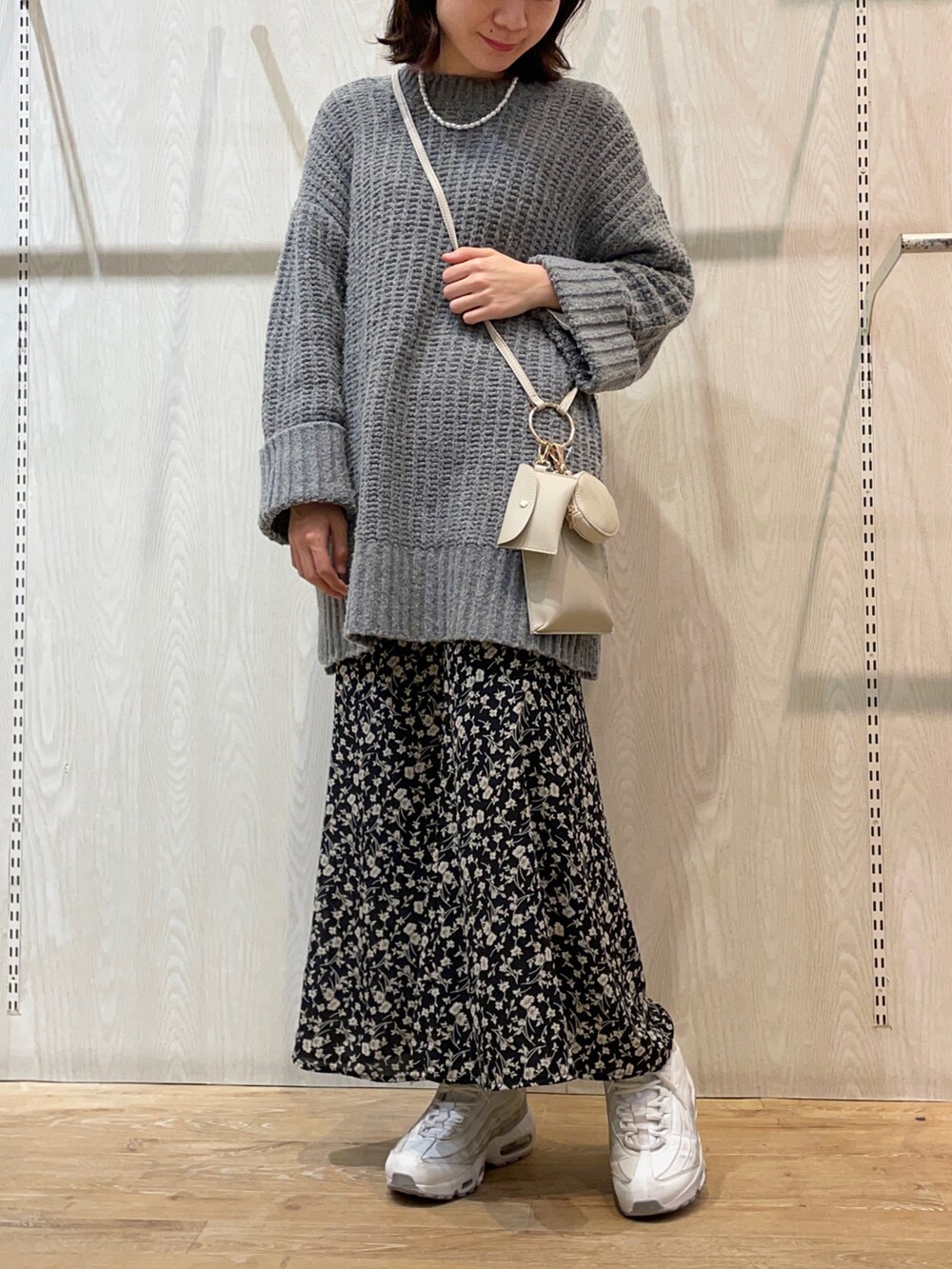 グレー系のニット/セーター、ブラック系のスカート、ホワイト系のトートバッグを着用したレディースの冬コーディネートの2枚目の写真