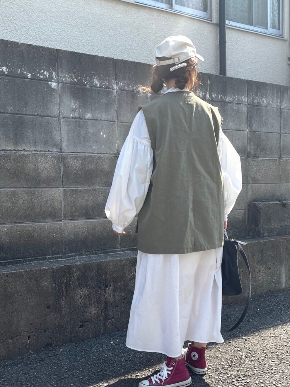 ホワイト系のシャツワンピース、グリーン系のベストを着用したレディースの春コーディネートの4枚目の写真