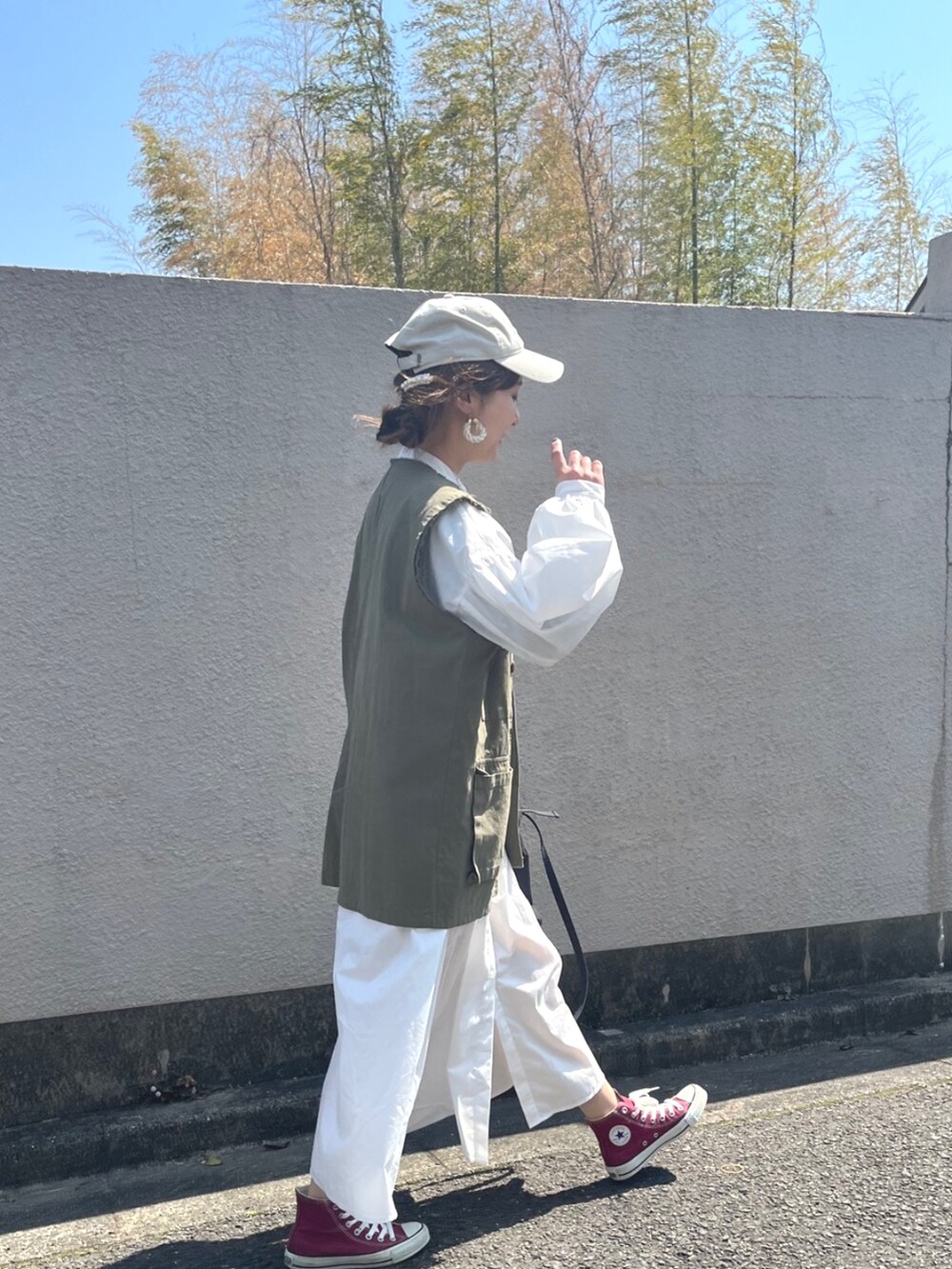 ホワイト系のシャツワンピース、グリーン系のベストを着用したレディースの春コーディネートの2枚目の写真