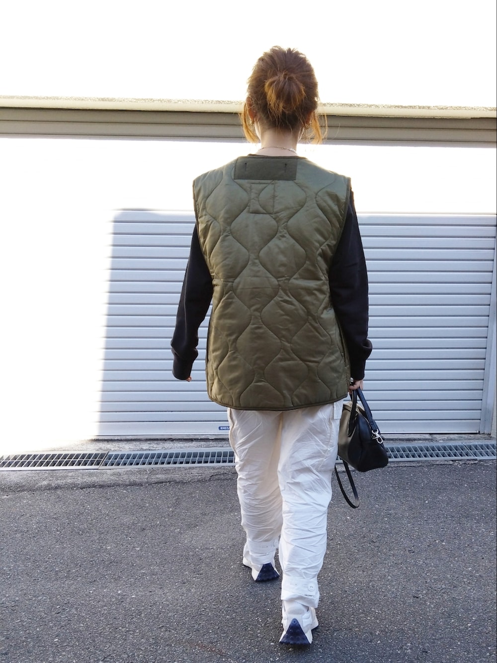 ブラック系のスウェット、グリーン系のベスト、ホワイト系のカーゴパンツを着用したレディースの冬コーディネートの3枚目の写真