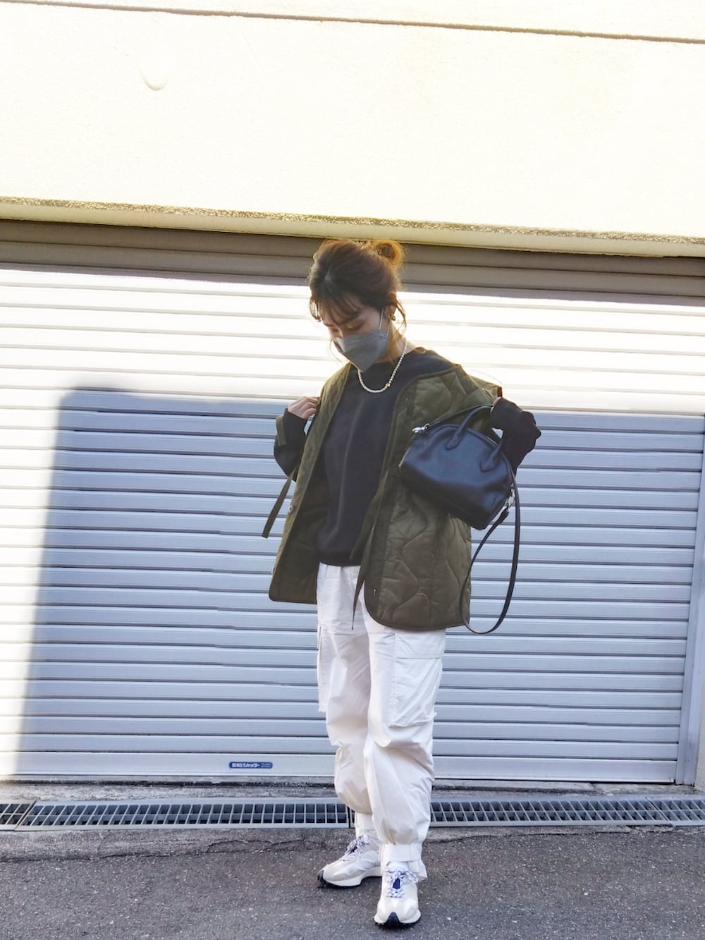 ブラック系のスウェット、グリーン系のベスト、ホワイト系のカーゴパンツを着用したレディースの冬コーディネートの2枚目の写真