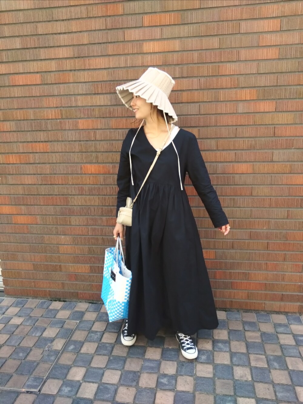 ブルー系のかごバッグ、ブラック系のスニーカー、ホワイト系のハットを着用したレディースの春コーディネートの3枚目の写真