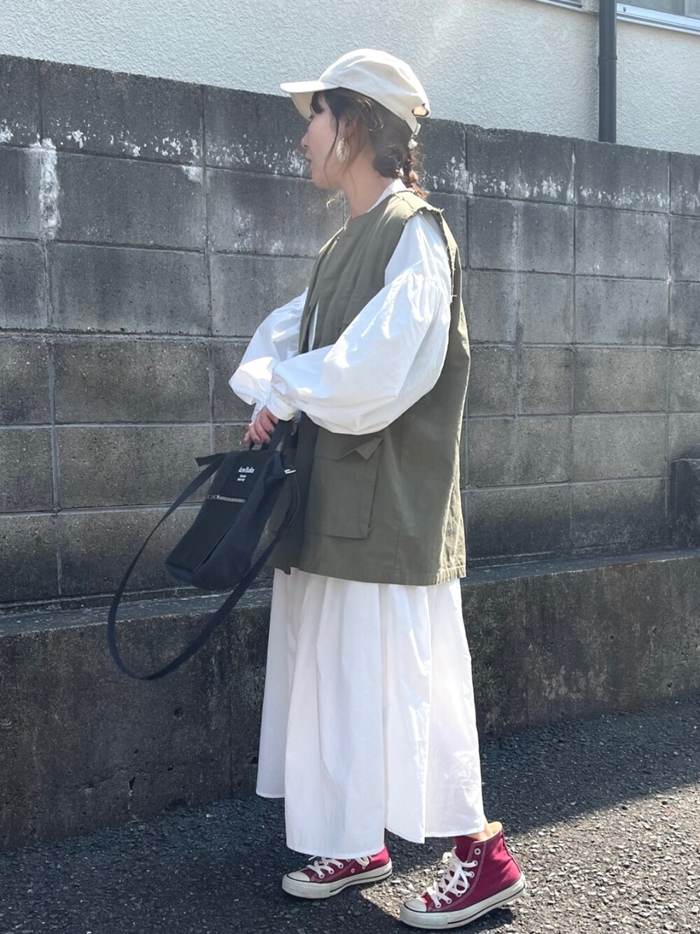 ホワイト系のシャツワンピース、グリーン系のベストを着用したレディースの春コーディネートの5枚目の写真