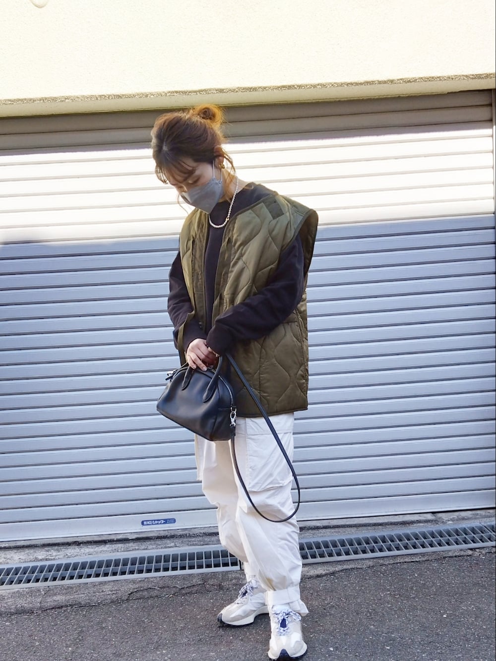 ブラック系のスウェット、グリーン系のベスト、ホワイト系のカーゴパンツを着用したレディースの冬コーディネートの4枚目の写真