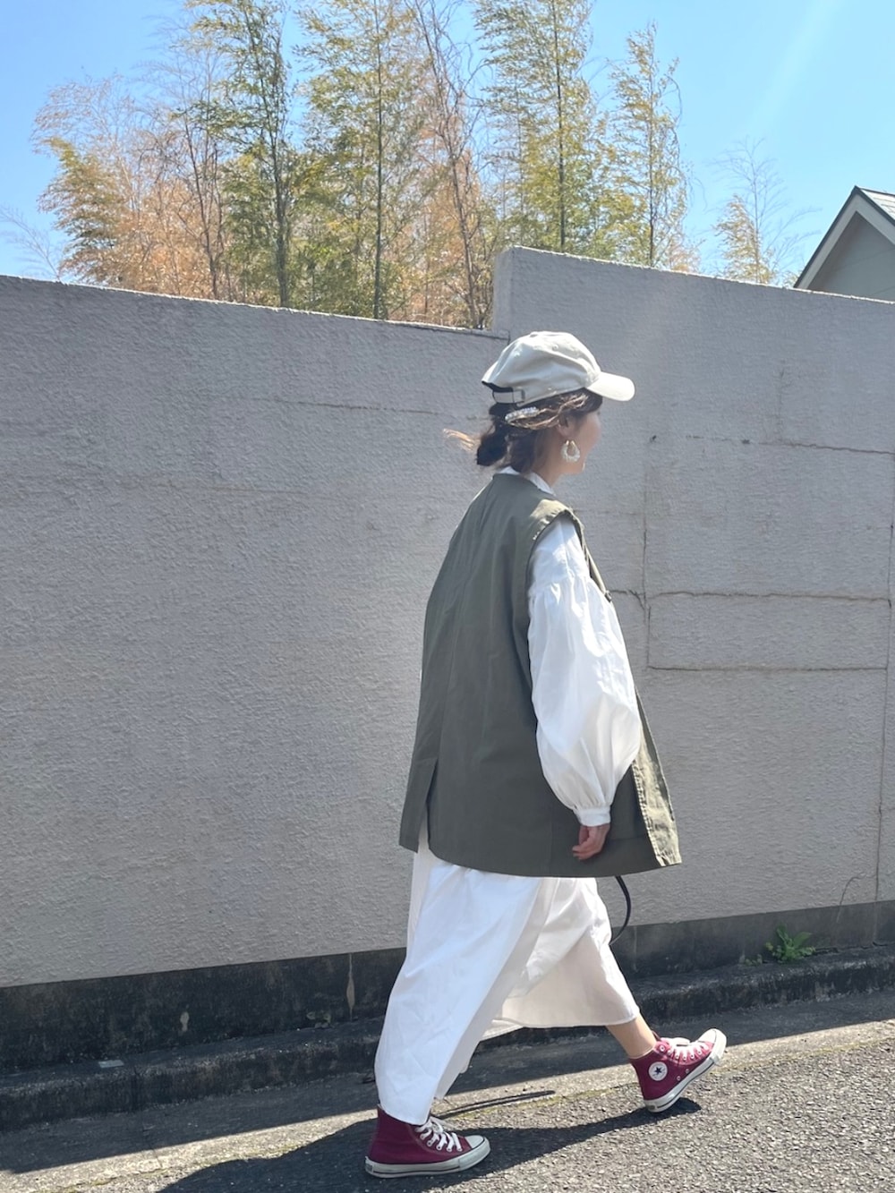 ホワイト系のシャツワンピース、グリーン系のベストを着用したレディースの春コーディネートの3枚目の写真