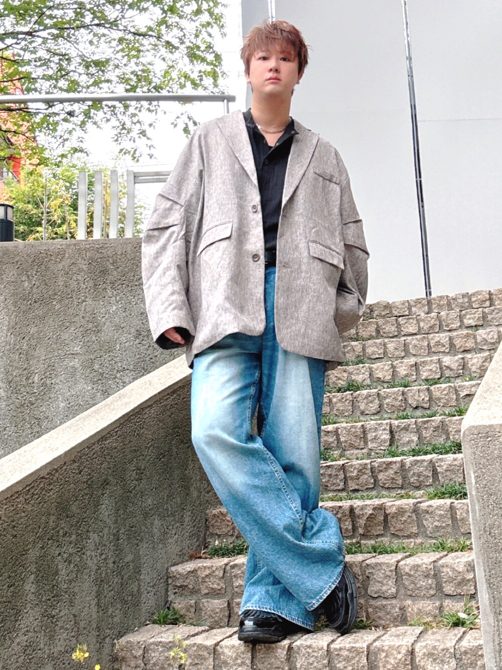 ブルー系のデニムパンツ、ブラック系のTシャツ/カットソー、ベージュ系のテーラードジャケットを着用したメンズの春コーディネートの3枚目の写真