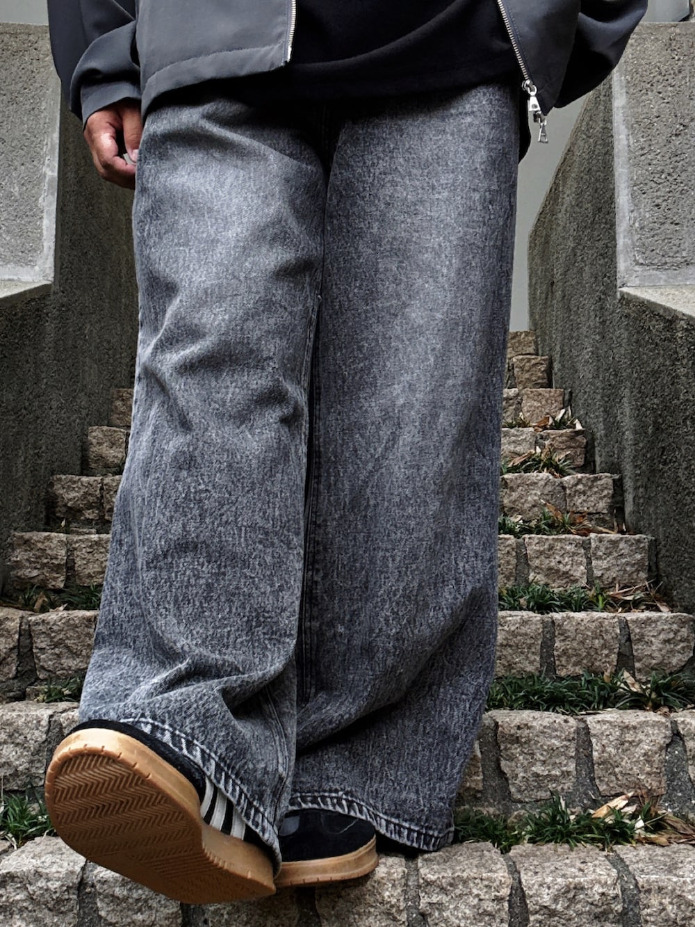 ブラック系のデニムパンツ、ブラック系のTシャツ/カットソー、グレー系のブルゾンを着用したメンズの秋コーディネートの5枚目の写真