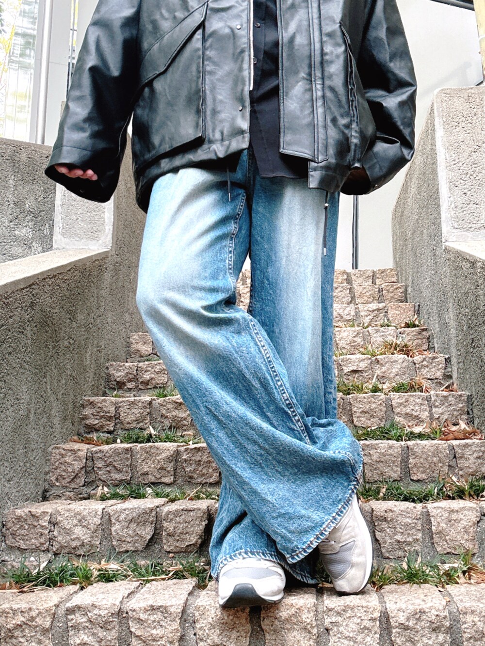 ブルー系のデニムパンツ、グレー系のスニーカー、ブラック系のブルゾンを着用したメンズの秋コーディネートの5枚目の写真