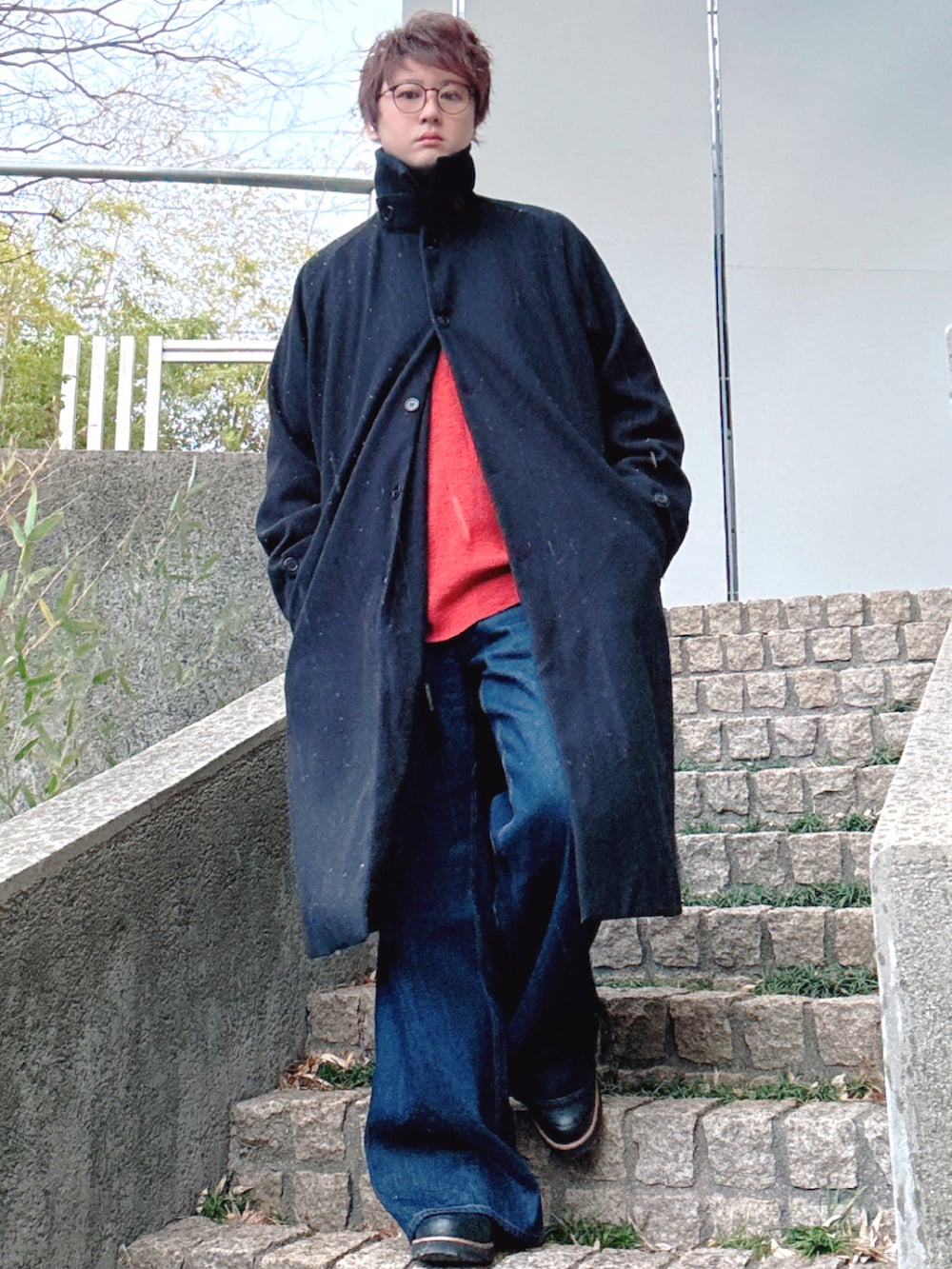 ブルー系のデニムパンツ、ブラウン系のニット/セーター、ブラック系のステンカラーコートを着用したメンズの冬コーディネートの2枚目の写真