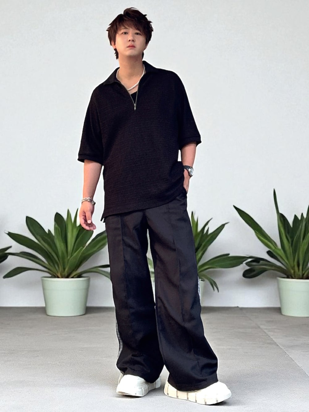 ブラック系のスラックス、ブラック系のポロシャツ、ホワイト系のスニーカーを着用したメンズの夏コーディネートの3枚目の写真