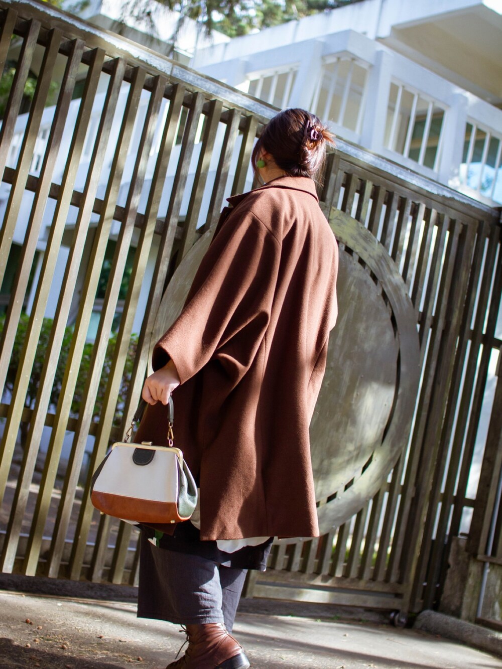 ブラウン系のムートンコート、ブラック系のワンピース、その他のトートバッグを着用したレディースの夏コーディネートの2枚目の写真