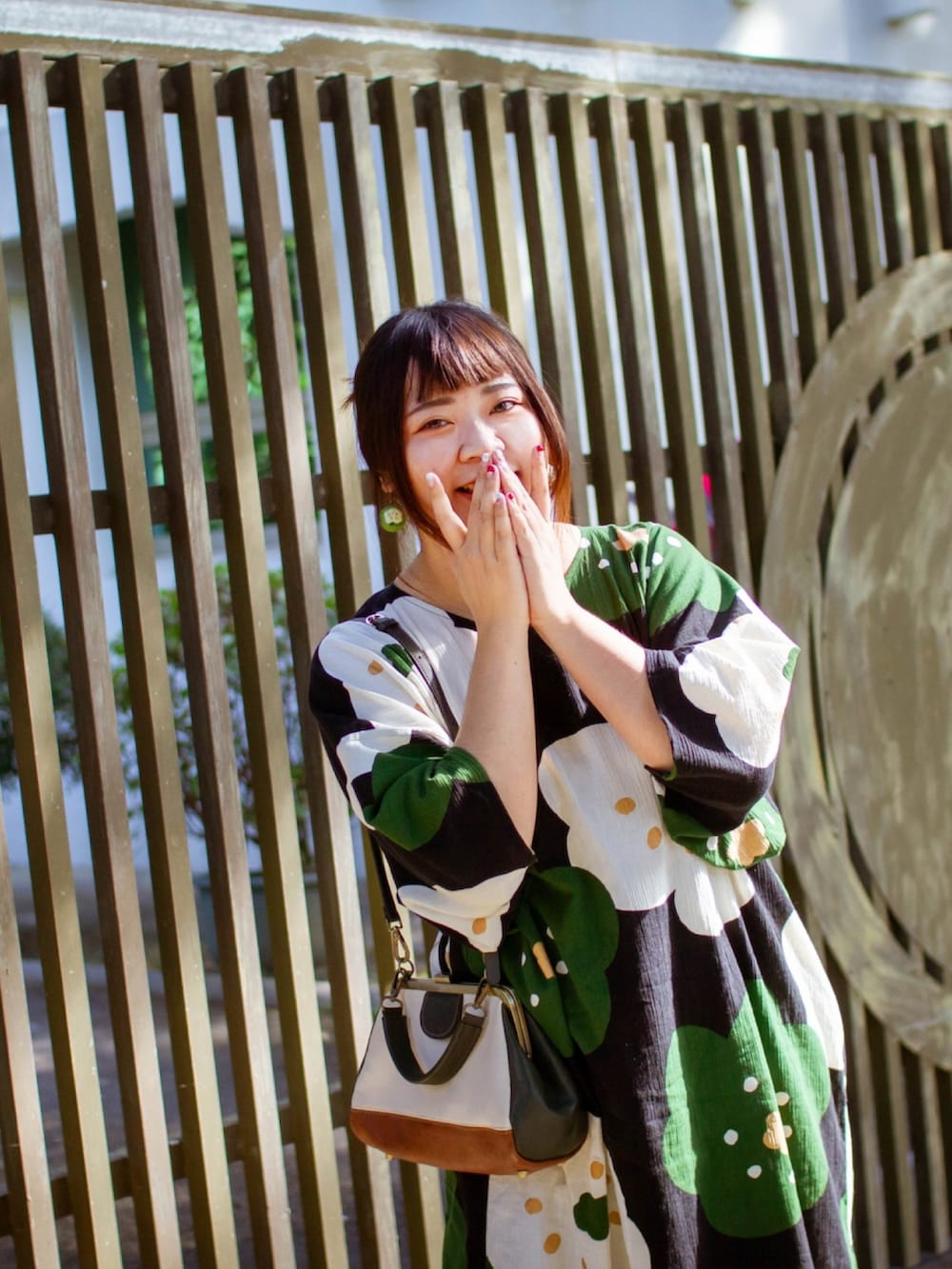 ブラウン系のムートンコート、ブラック系のワンピース、その他のトートバッグを着用したレディースの夏コーディネートの5枚目の写真