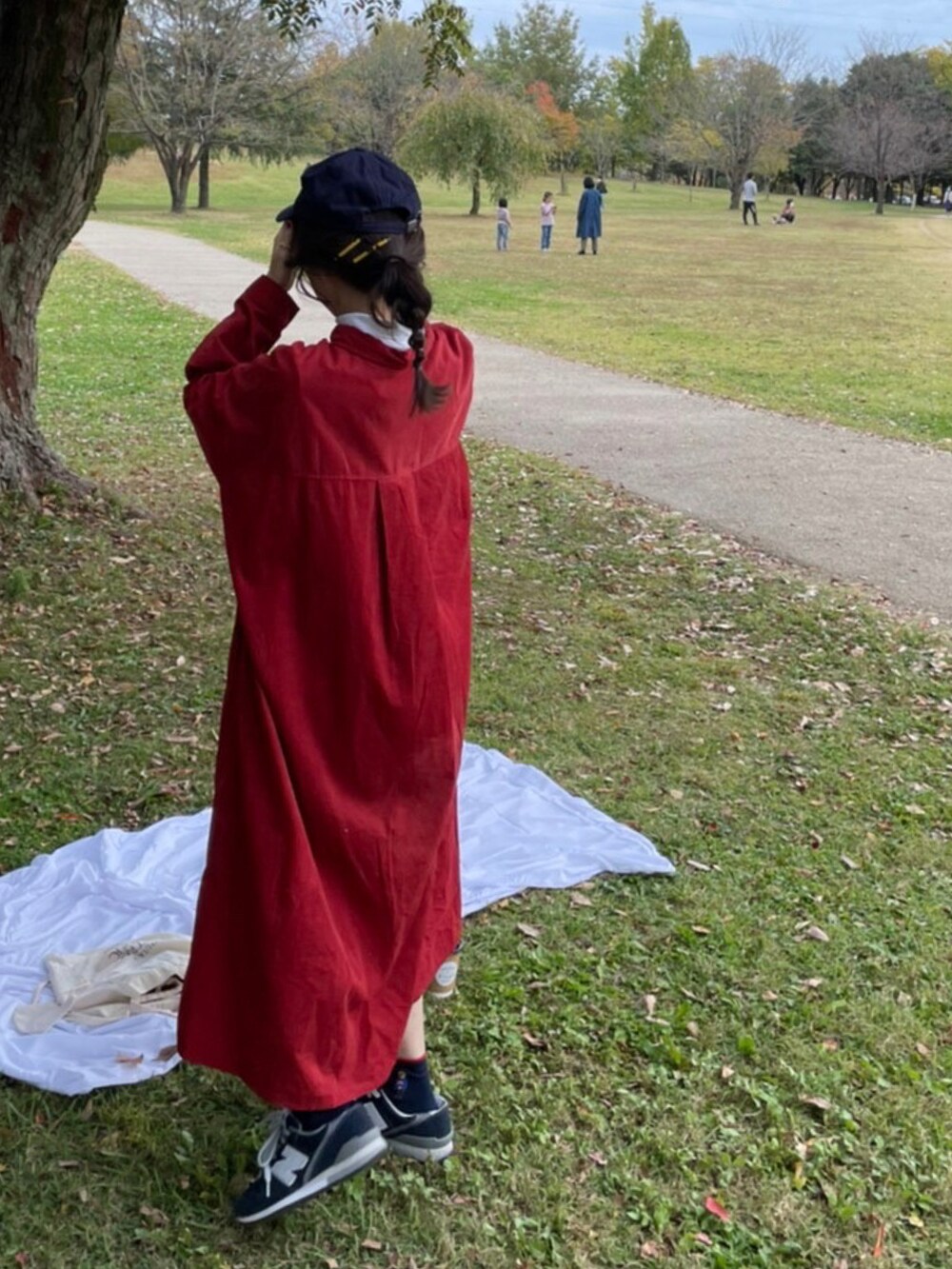 ブルー系のサロペット/オーバーオール、ブルー系のデニムジャケット、レッド系のワンピースを着用したレディースの秋コーディネートの2枚目の写真