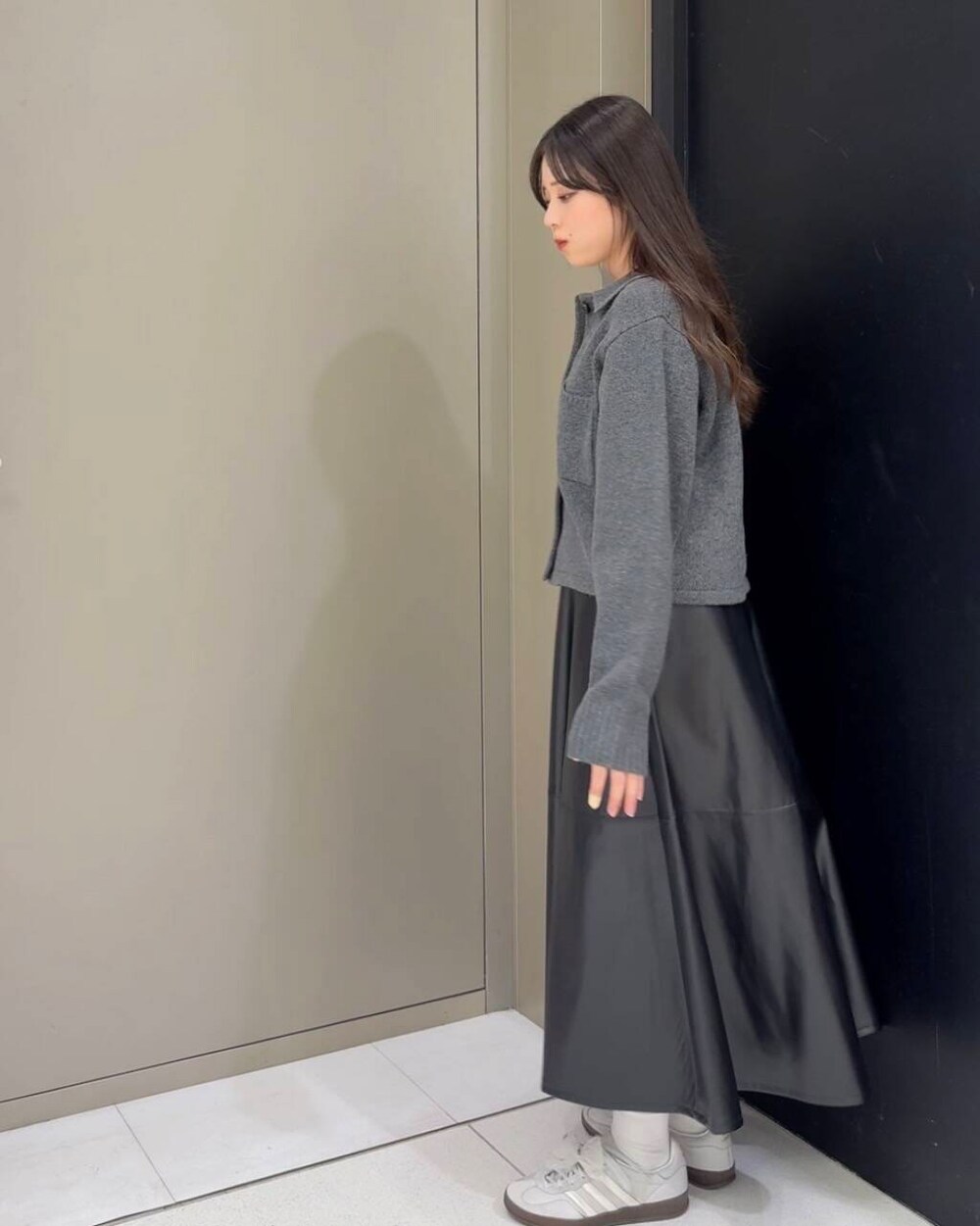 レッド系のショルダーバッグ、ブラック系のスカート、グレー系のニット/セーターを着用したレディースの秋コーディネートの4枚目の写真