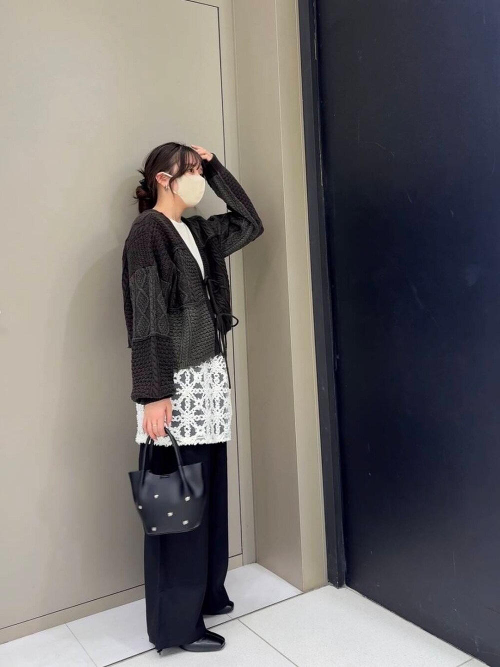 ブラック系のスラックス、ブラック系のブーツ、ホワイト系のニット/セーターを着用したレディースの冬コーディネートの2枚目の写真