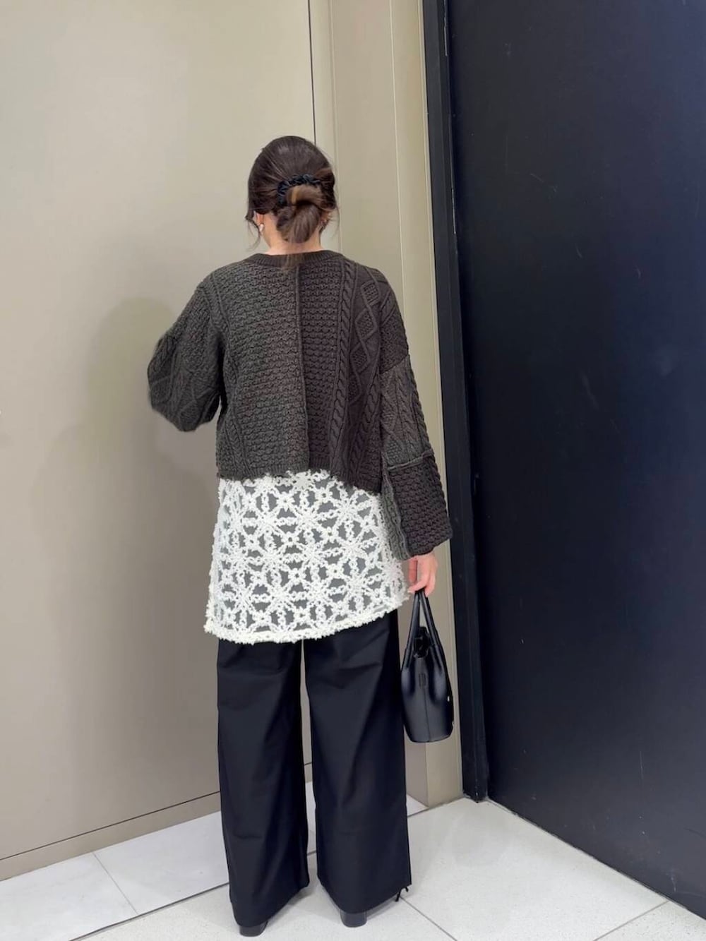 ブラック系のスラックス、ブラック系のブーツ、ホワイト系のニット/セーターを着用したレディースの冬コーディネートの5枚目の写真