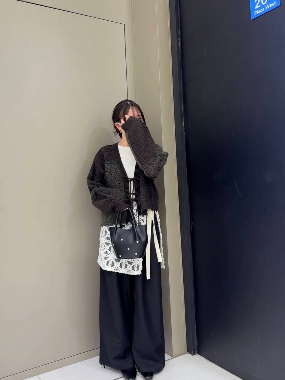 ブラック系のスラックス、ブラック系のブーツ、ホワイト系のニット/セーターを着用したレディースの冬コーディネートの3枚目の写真