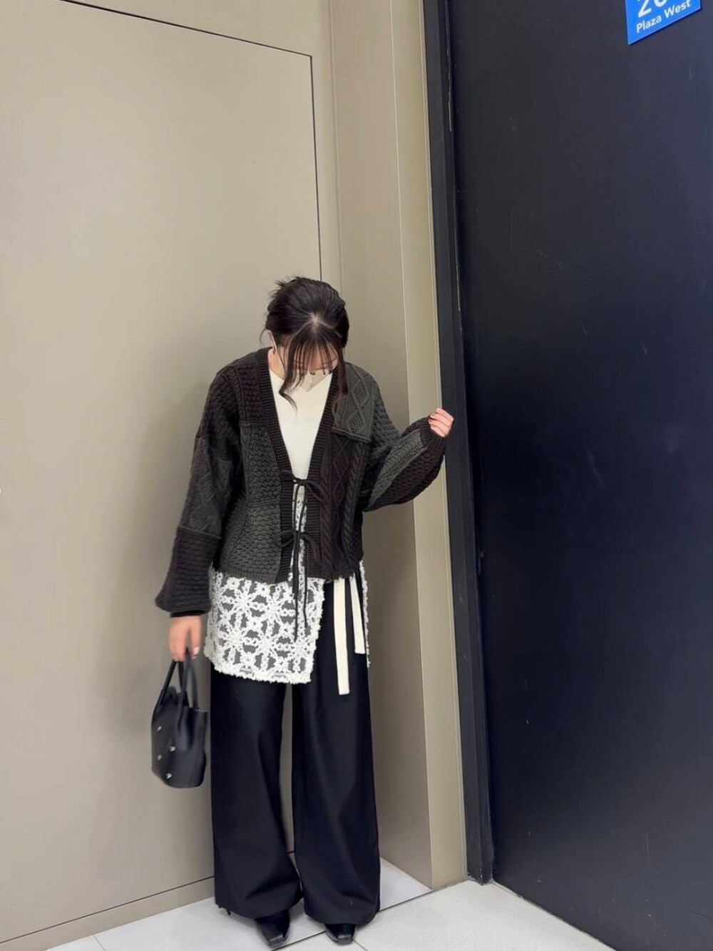 ブラック系のスラックス、ブラック系のブーツ、ホワイト系のニット/セーターを着用したレディースの冬コーディネートの4枚目の写真