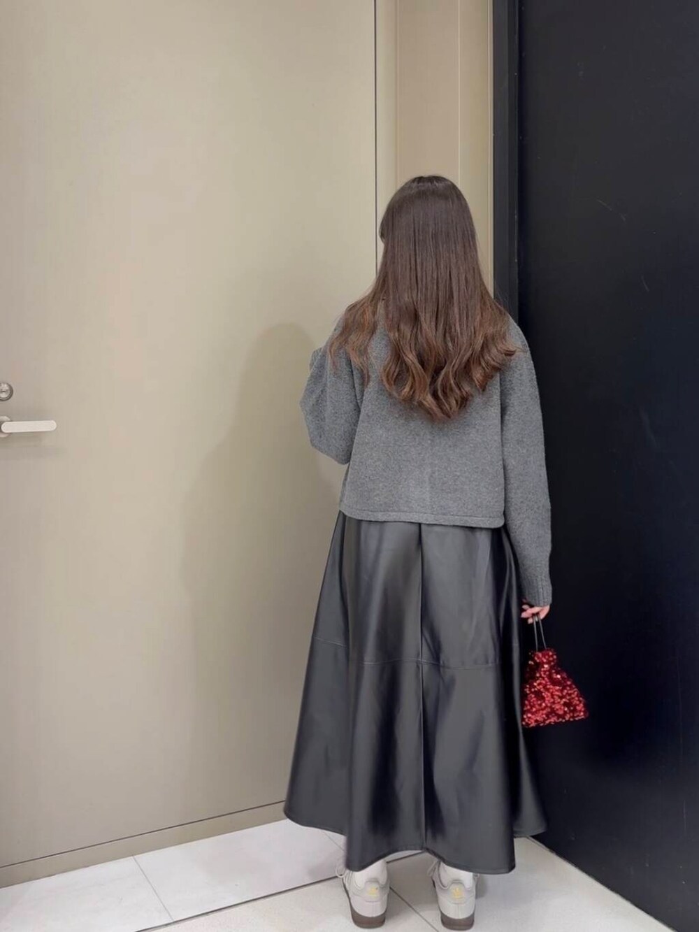 レッド系のショルダーバッグ、ブラック系のスカート、グレー系のニット/セーターを着用したレディースの秋コーディネートの5枚目の写真