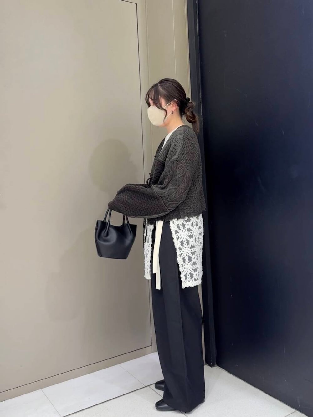 ブラック系のスラックス、ブラック系のブーツ、ホワイト系のニット/セーターを着用したレディースの冬コーディネートの6枚目の写真