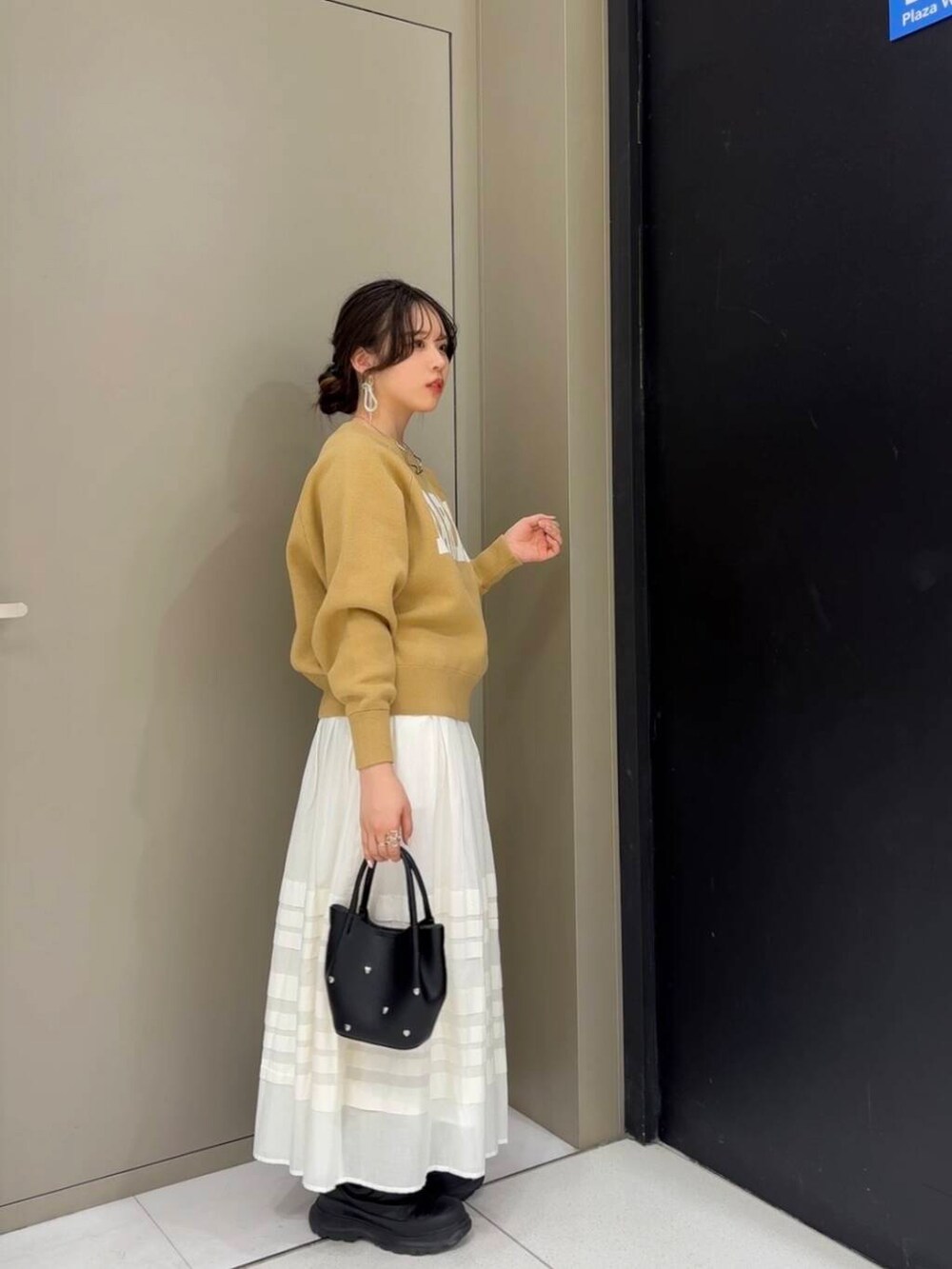 ベージュ系のニット/セーター、ホワイト系のスカート、ブラック系のショルダーバッグを着用したレディースの冬コーディネートの3枚目の写真