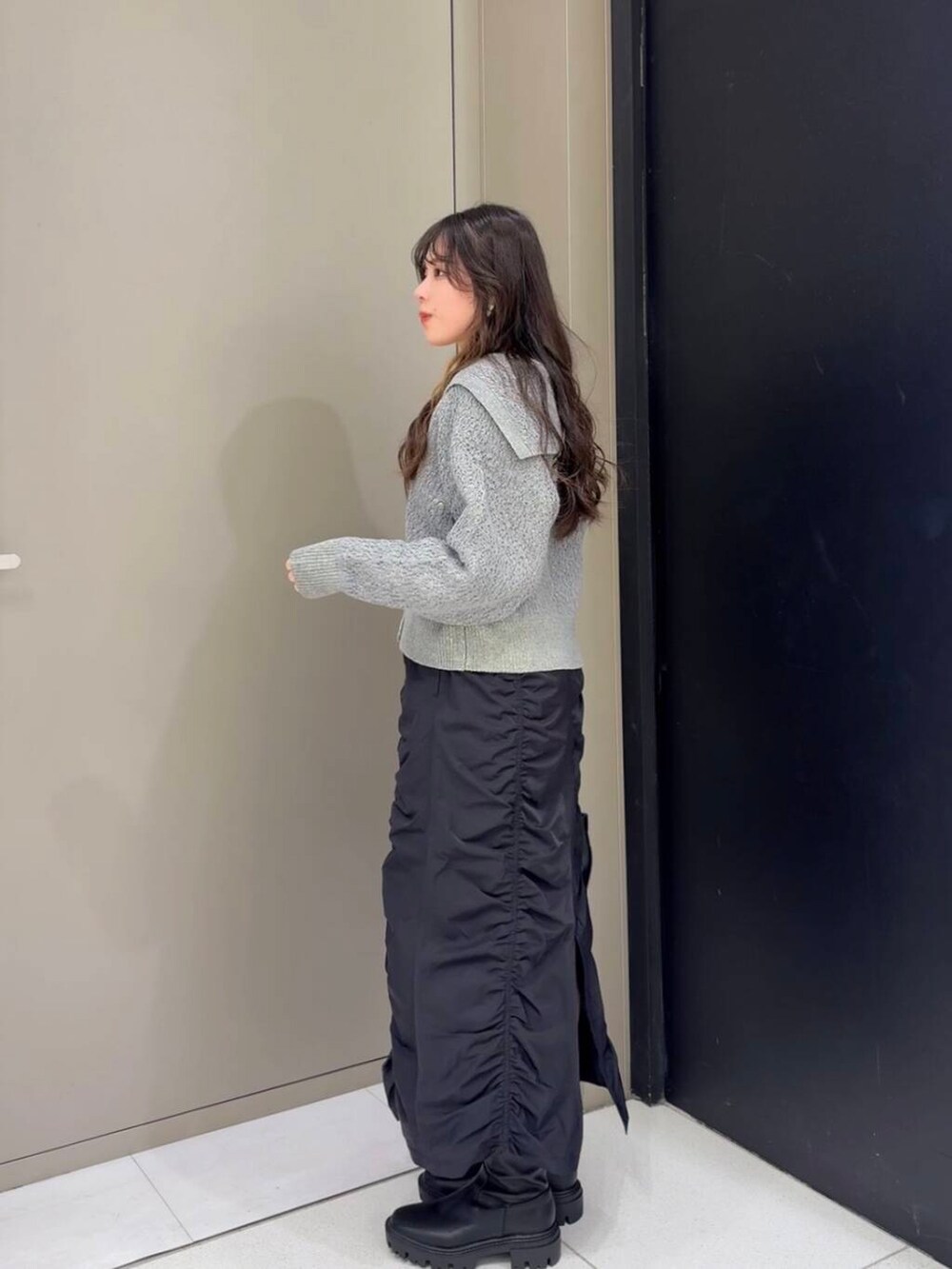 ブラック系のブーツ、ブラック系のスカート、ブラック系のショルダーバッグを着用したレディースの冬コーディネートの4枚目の写真