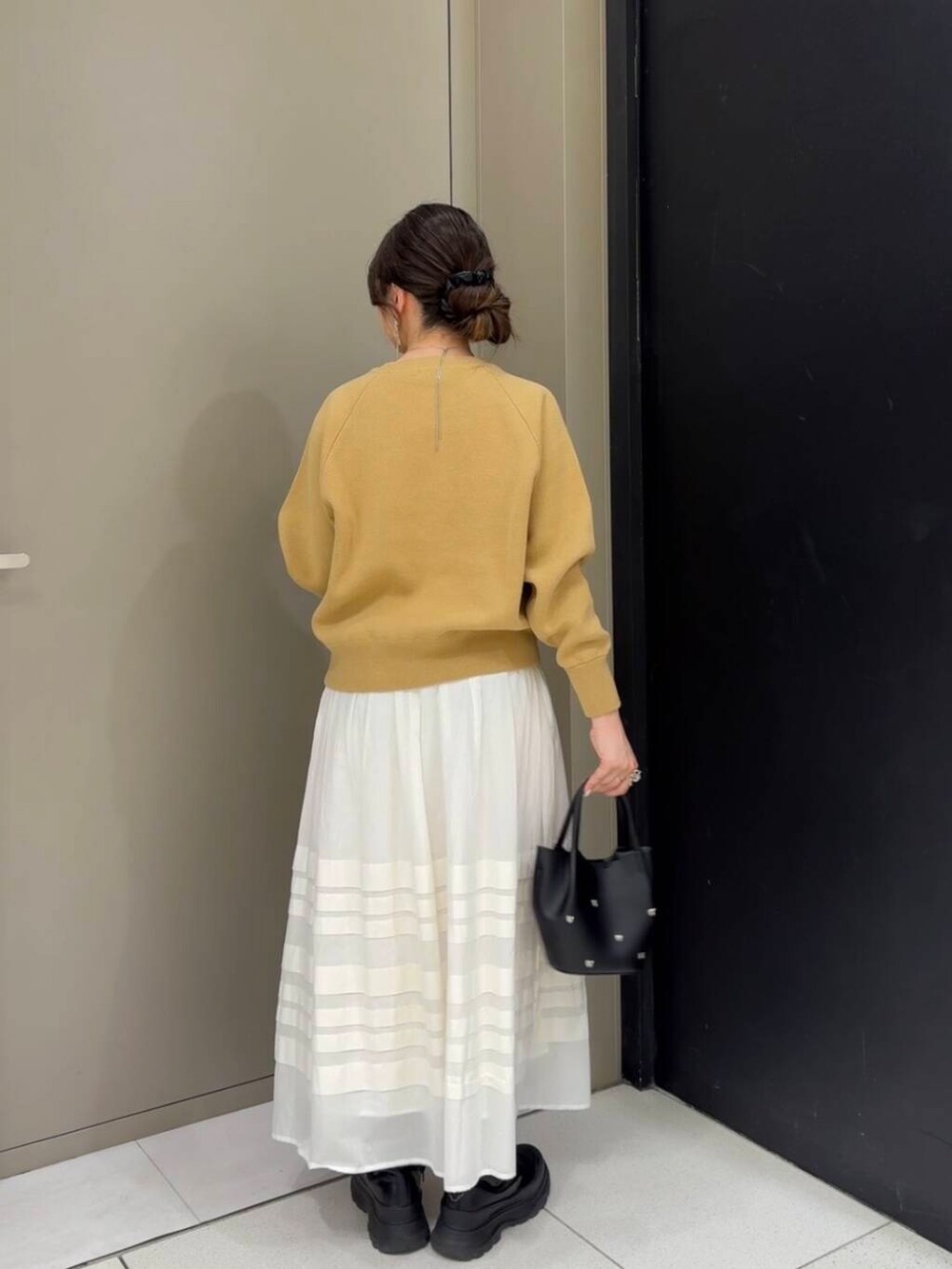 ベージュ系のニット/セーター、ホワイト系のスカート、ブラック系のショルダーバッグを着用したレディースの冬コーディネートの5枚目の写真