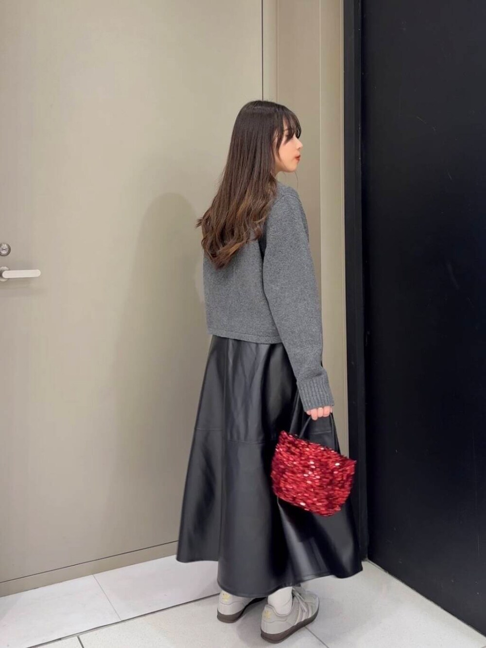 レッド系のショルダーバッグ、ブラック系のスカート、グレー系のニット/セーターを着用したレディースの秋コーディネートの3枚目の写真