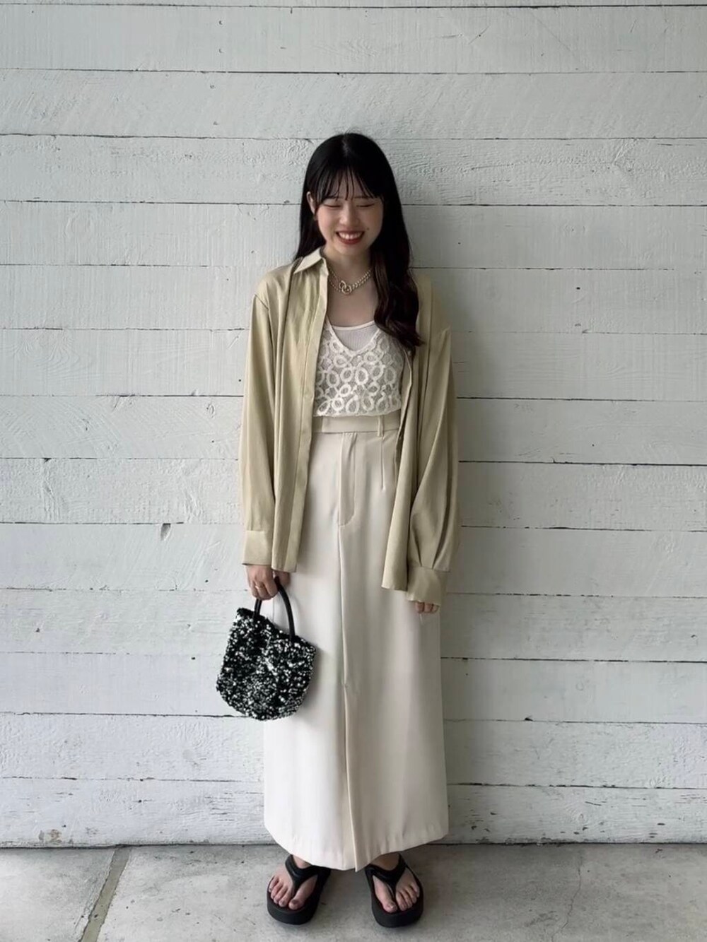 シルバー系のショルダーバッグ、ベージュ系のシャツ/ブラウス、ホワイト系のベストを着用したレディースの夏コーディネートの2枚目の写真