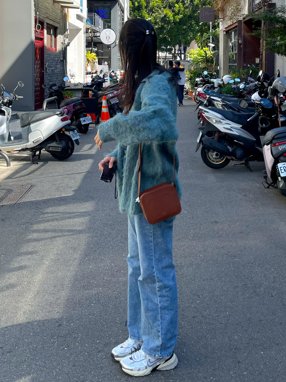 ブルー系のカーディガン/ボレロ、ブルー系のデニムパンツ、ホワイト系のスニーカーを着用したレディースの冬コーディネートの2枚目の写真