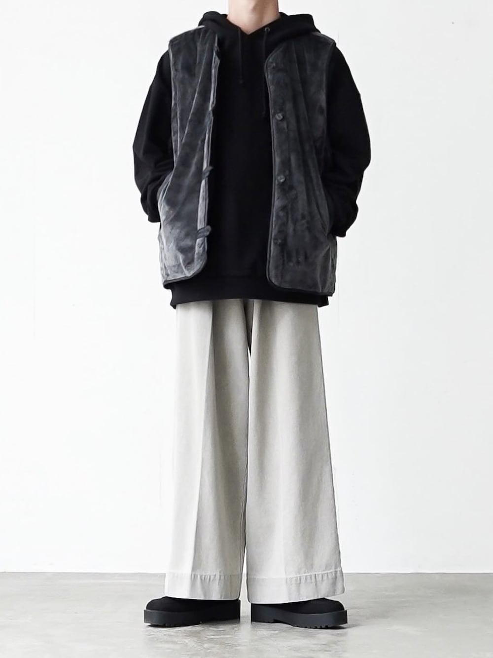 グレー系のベスト、ブラック系のパーカー、グレー系のデニムパンツを着用したメンズの秋コーディネートの5枚目の写真