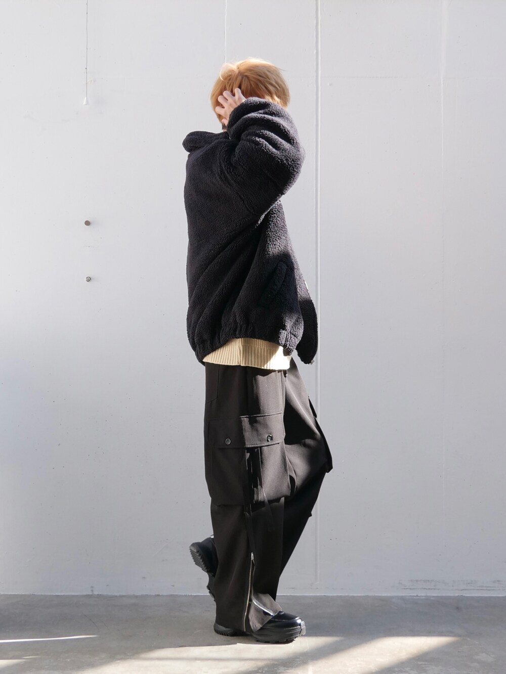 ブラック系のブルゾン、ホワイト系のニット/セーター、ブラック系のカーゴパンツを着用したメンズの秋コーディネートの3枚目の写真