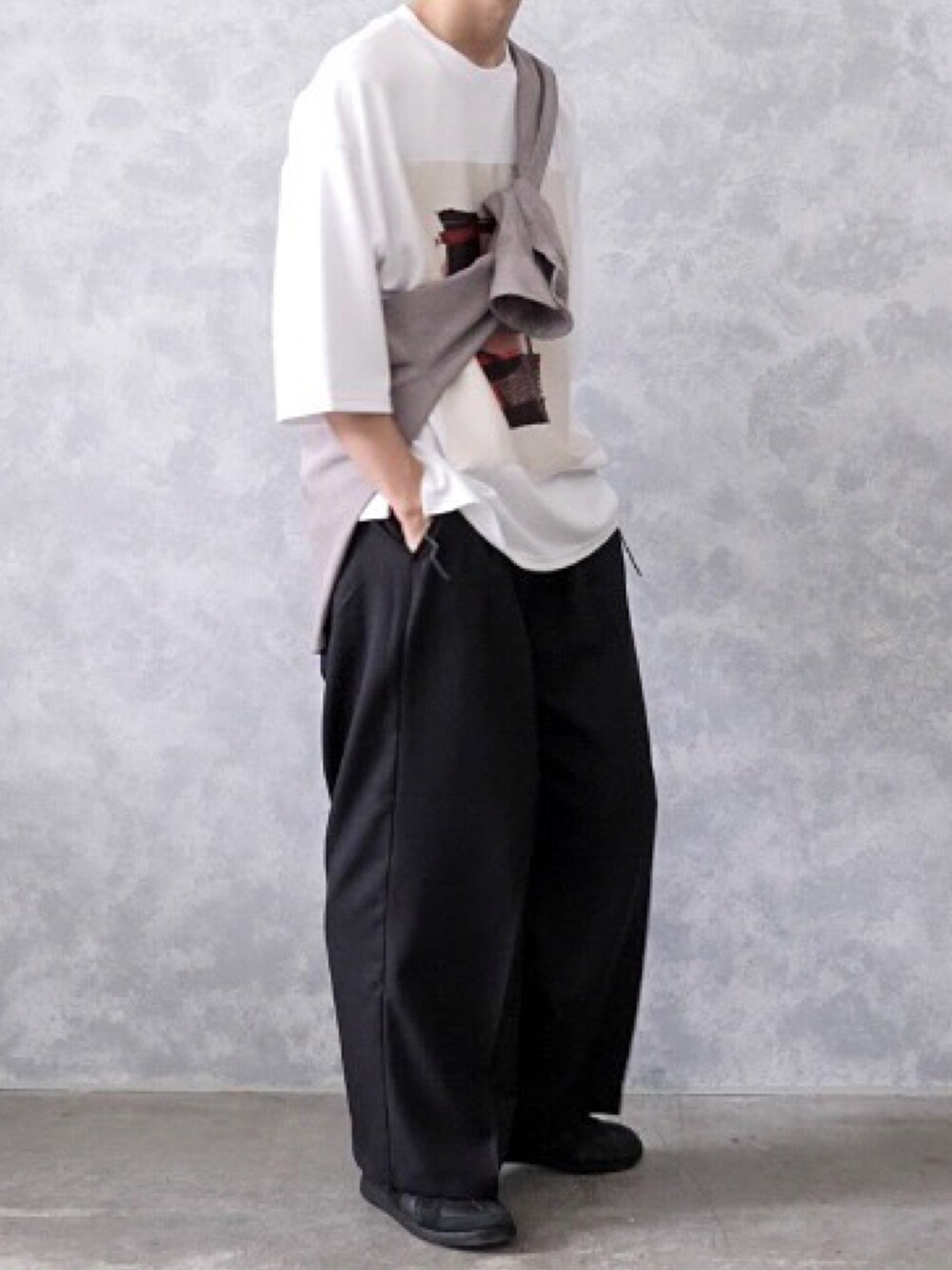 ブラック系のスラックス、ホワイト系のTシャツ/カットソー、ブラック系のスニーカーを着用したメンズの春コーディネートの2枚目の写真
