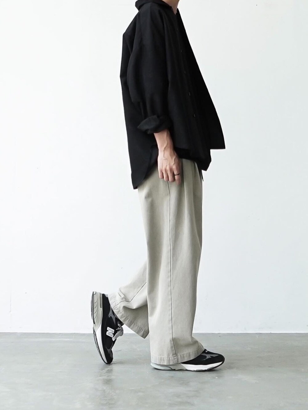 ブラック系のTシャツ/カットソー、ベージュ系のデニムパンツ、ブラック系のスニーカーを着用したメンズの夏コーディネートの2枚目の写真