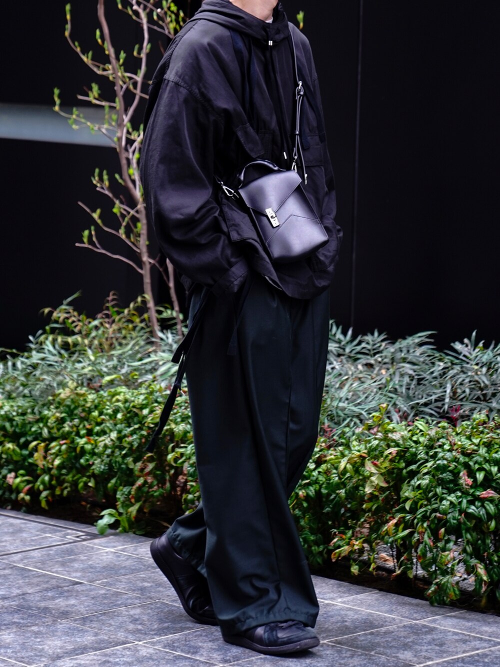 ブラック系のパーカー、グリーン系のその他パンツ、ブラック系のスニーカーを着用したメンズの春コーディネートの2枚目の写真