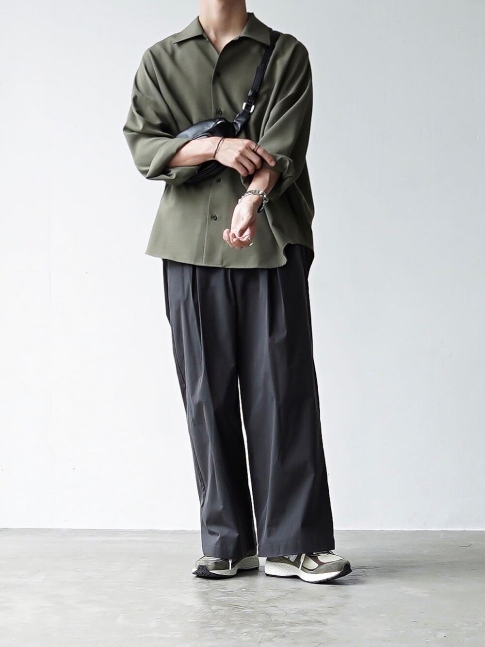 グレー系のチノパンツ、ブラック系のボディバッグ/ウエストポーチ、グリーン系のスニーカーを着用したメンズの夏コーディネートの2枚目の写真