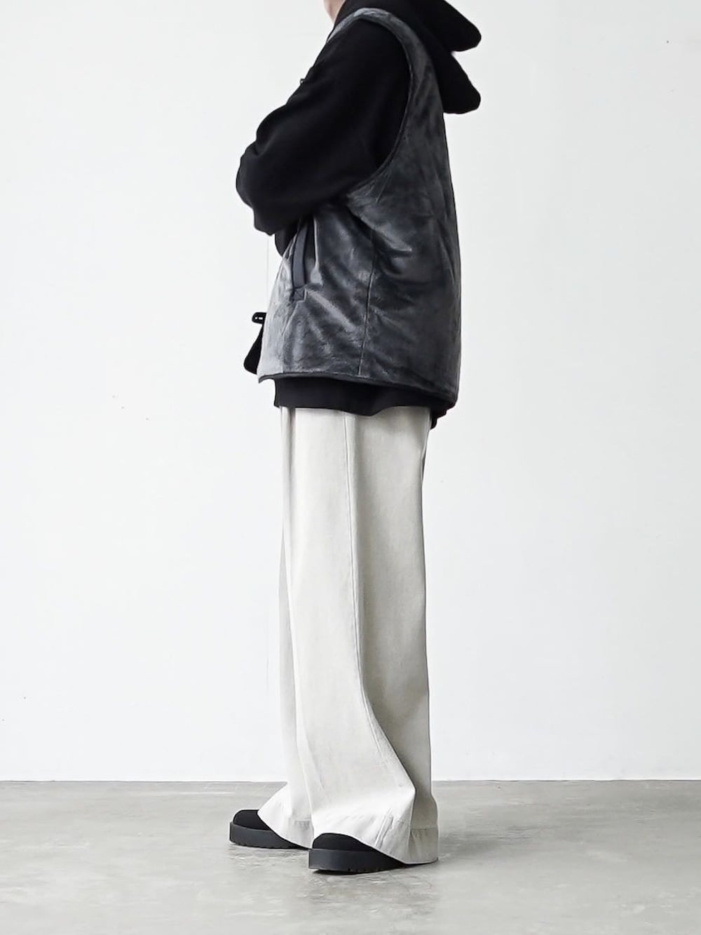 グレー系のベスト、ブラック系のパーカー、グレー系のデニムパンツを着用したメンズの秋コーディネートの2枚目の写真