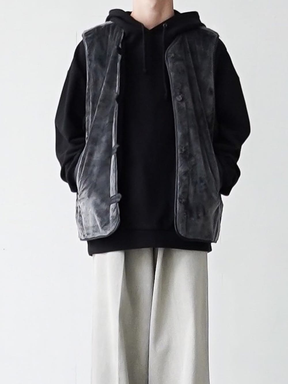 グレー系のベスト、ブラック系のパーカー、グレー系のデニムパンツを着用したメンズの秋コーディネートの3枚目の写真