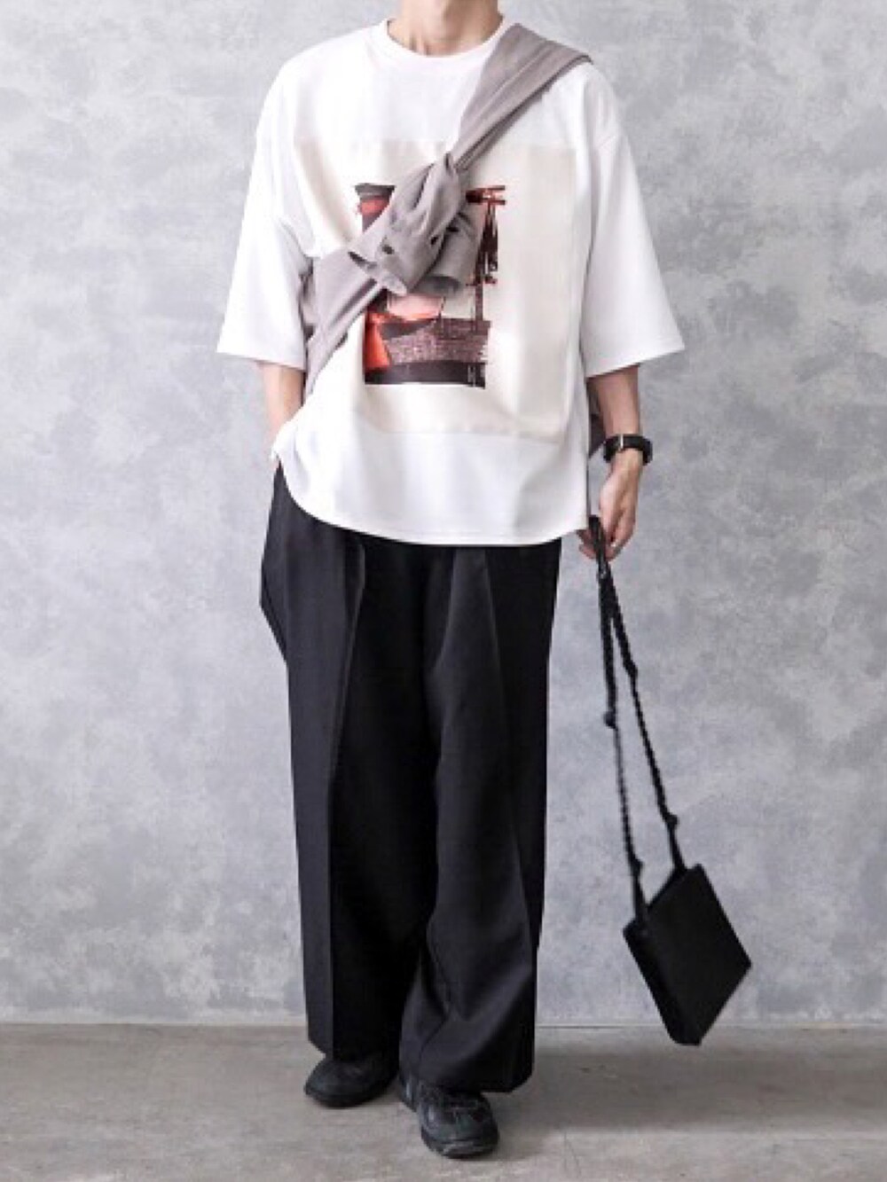 ブラック系のスラックス、ホワイト系のTシャツ/カットソー、ブラック系のスニーカーを着用したメンズの春コーディネートの3枚目の写真