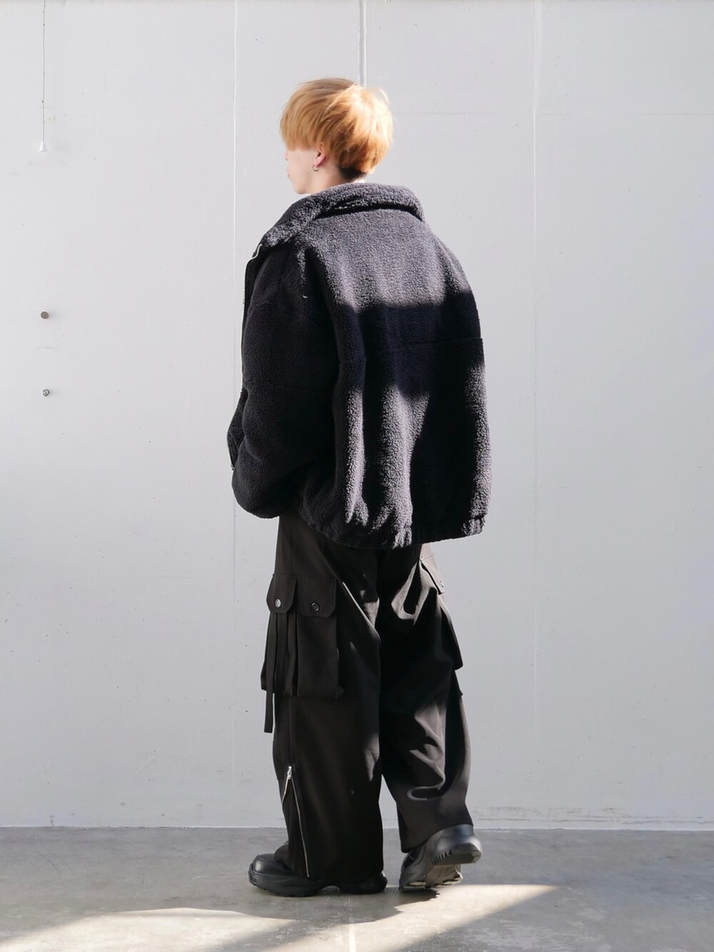 ブラック系のブルゾン、ホワイト系のニット/セーター、ブラック系のカーゴパンツを着用したメンズの秋コーディネートの4枚目の写真