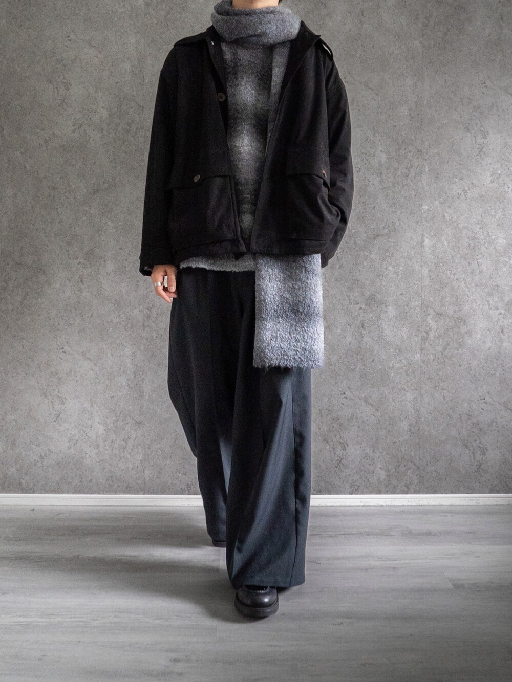 ブラック系のミリタリージャケット、グレー系のニット/セーター、ブラック系のスラックスを着用したメンズの冬コーディネートの3枚目の写真