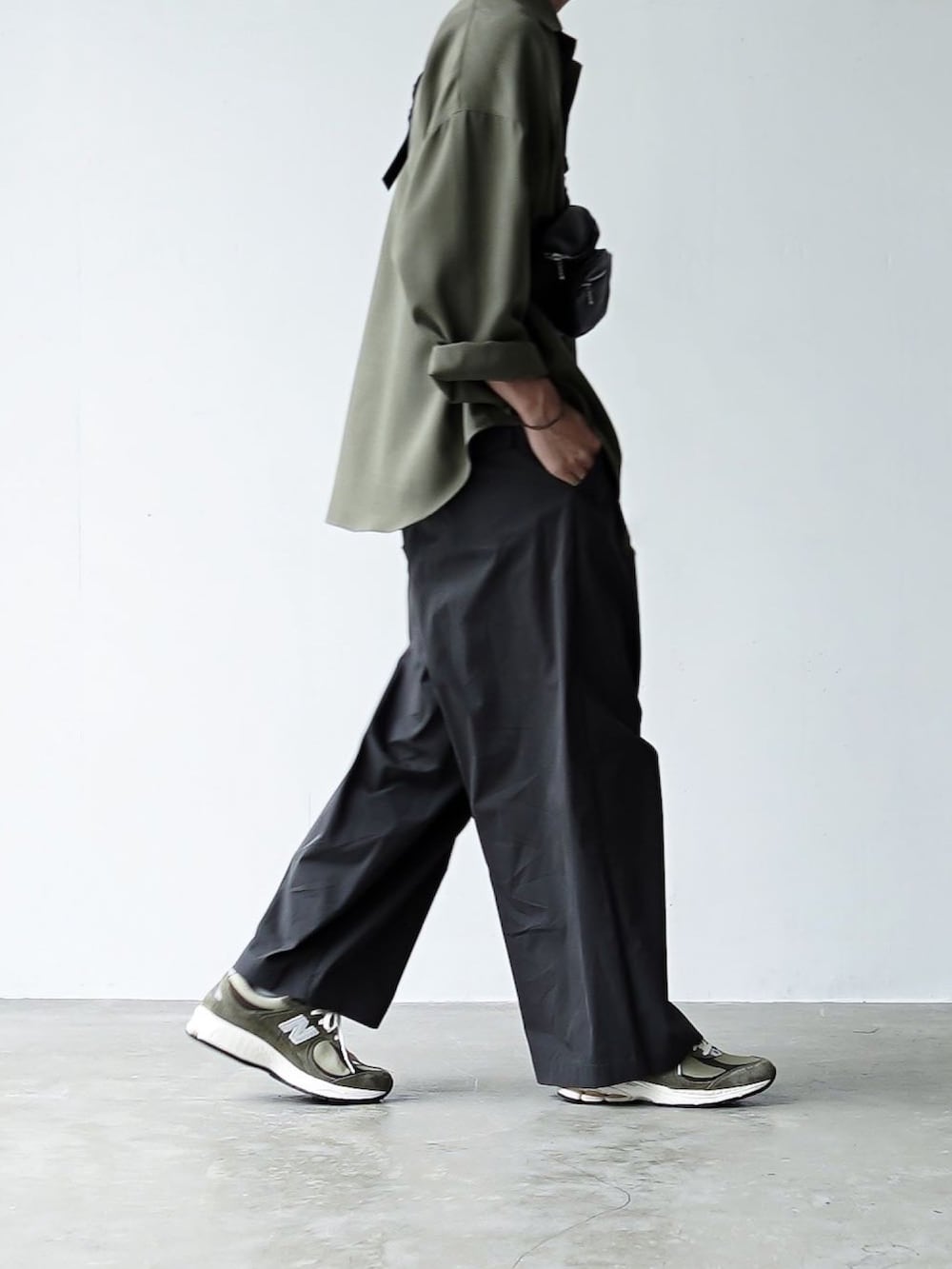 グレー系のチノパンツ、ブラック系のボディバッグ/ウエストポーチ、グリーン系のスニーカーを着用したメンズの夏コーディネートの5枚目の写真